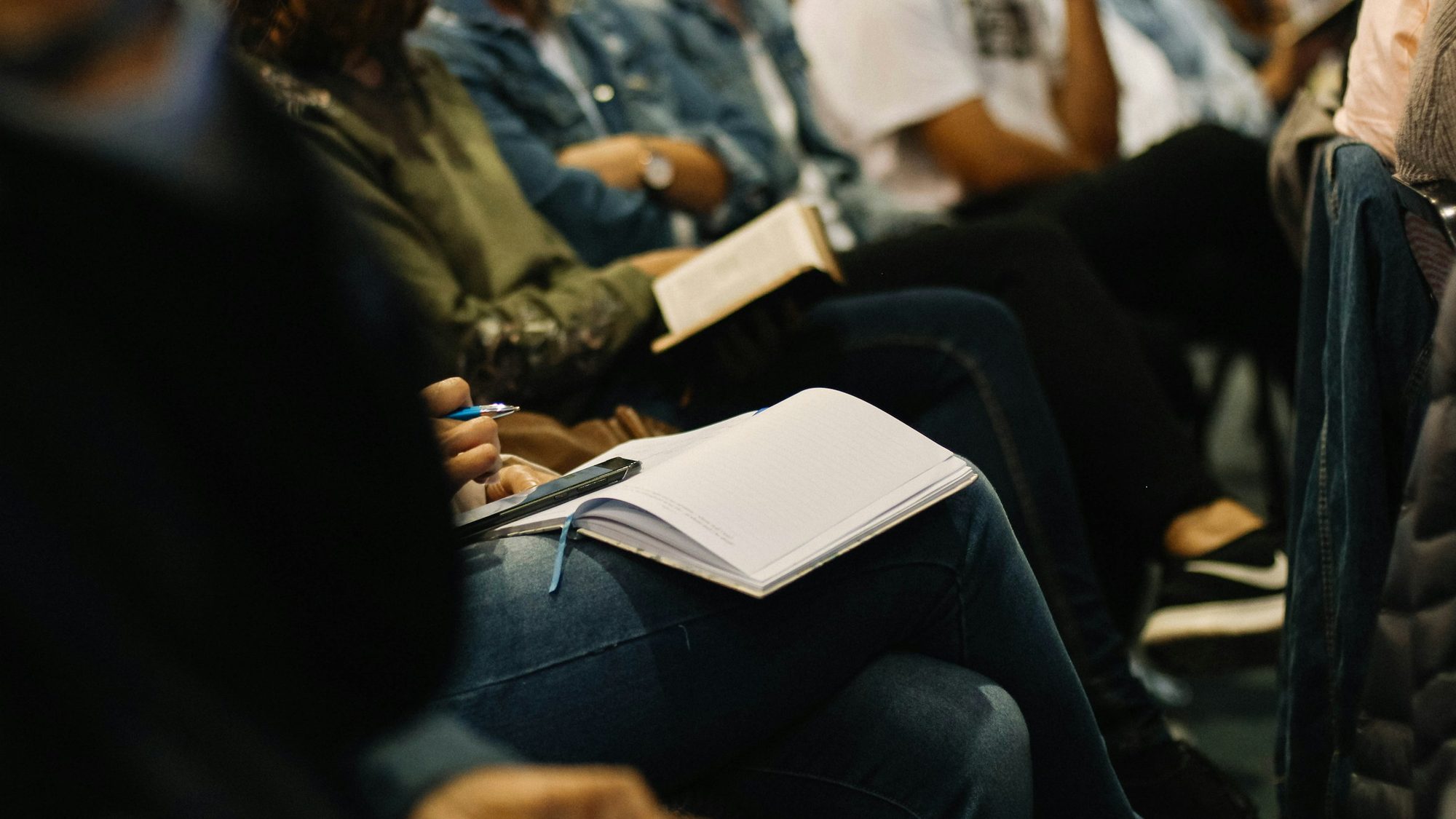People seated at a meeting, one with an open notebook on her lap