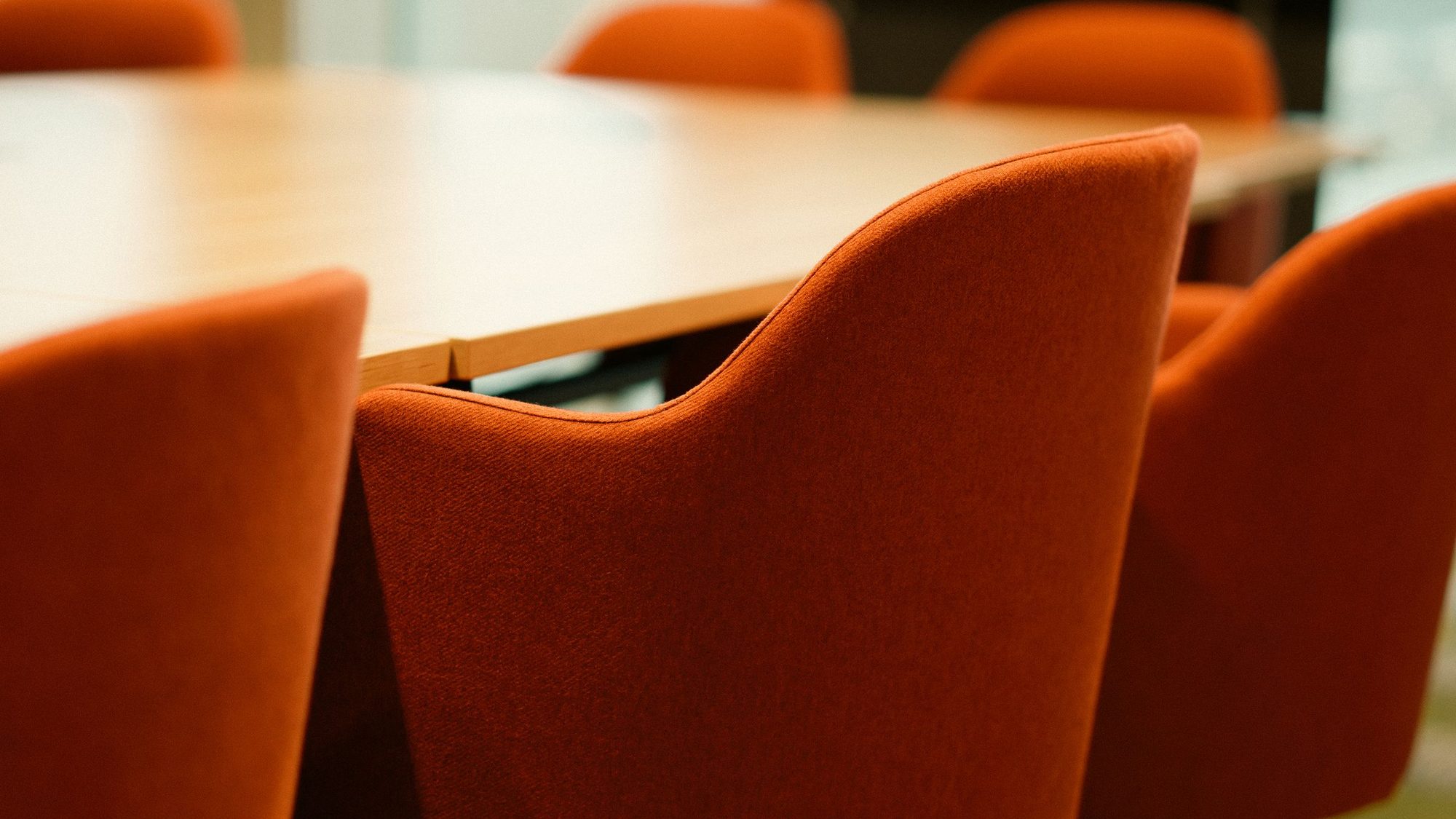 Orange chairs around a wooden conference table in a meeting room