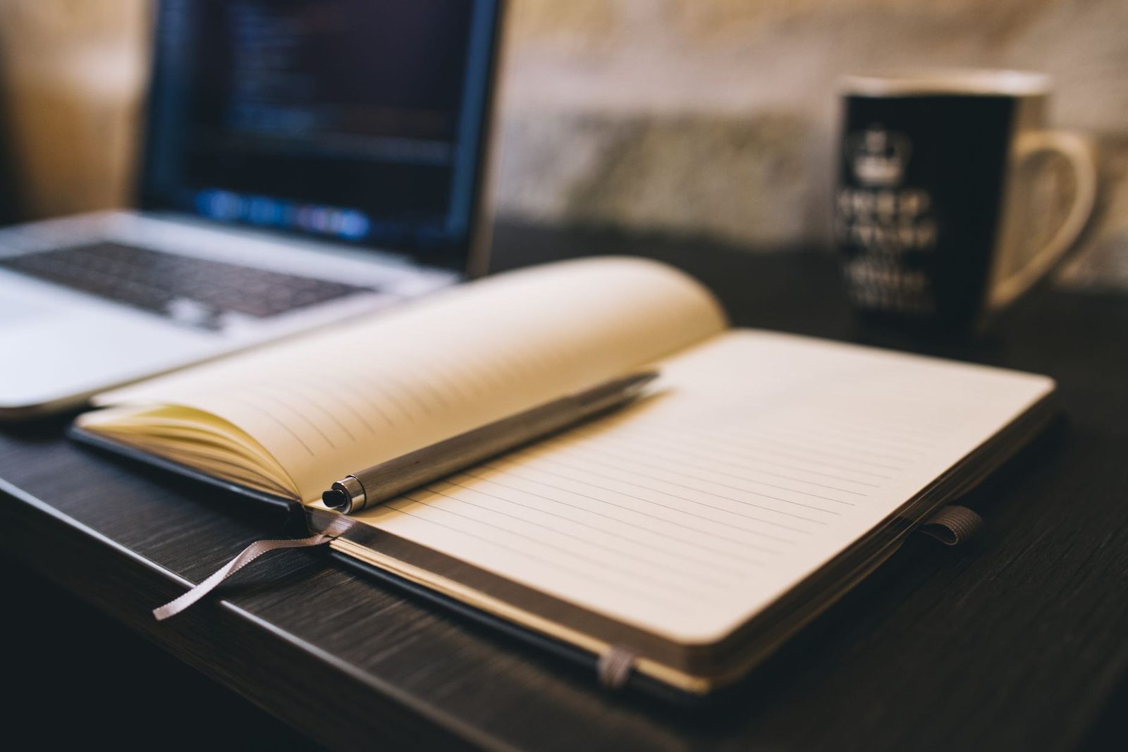 An open notebook and pen beside a laptop, field notes from a live texting program