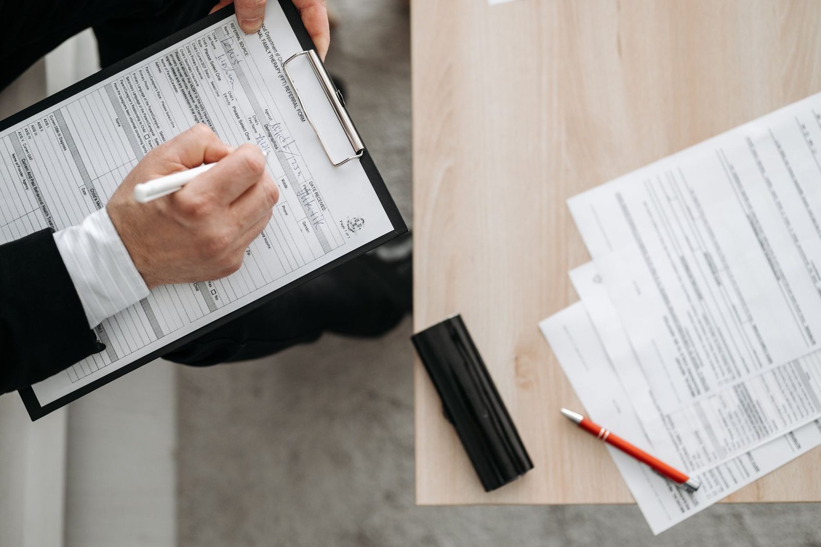 A person filling out a paper form at a desk, the opt-in moment that creates the consent record a texting program has to be able to produce later
