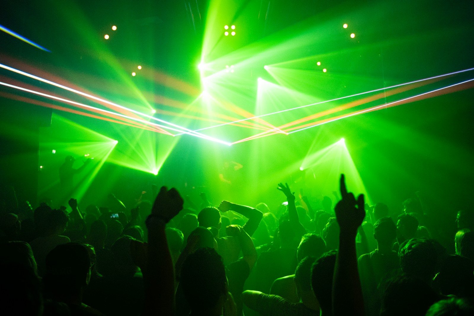 Crowd on a nightclub dance floor under stage lights, the event-night audience for nightclub SMS marketing