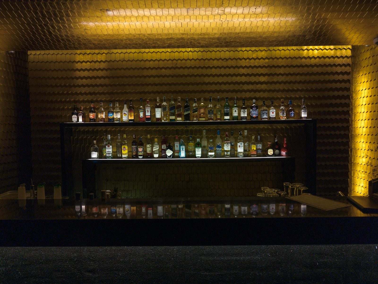 Dimly lit back bar lined with bottles, the neighborhood bar audience for SMS marketing