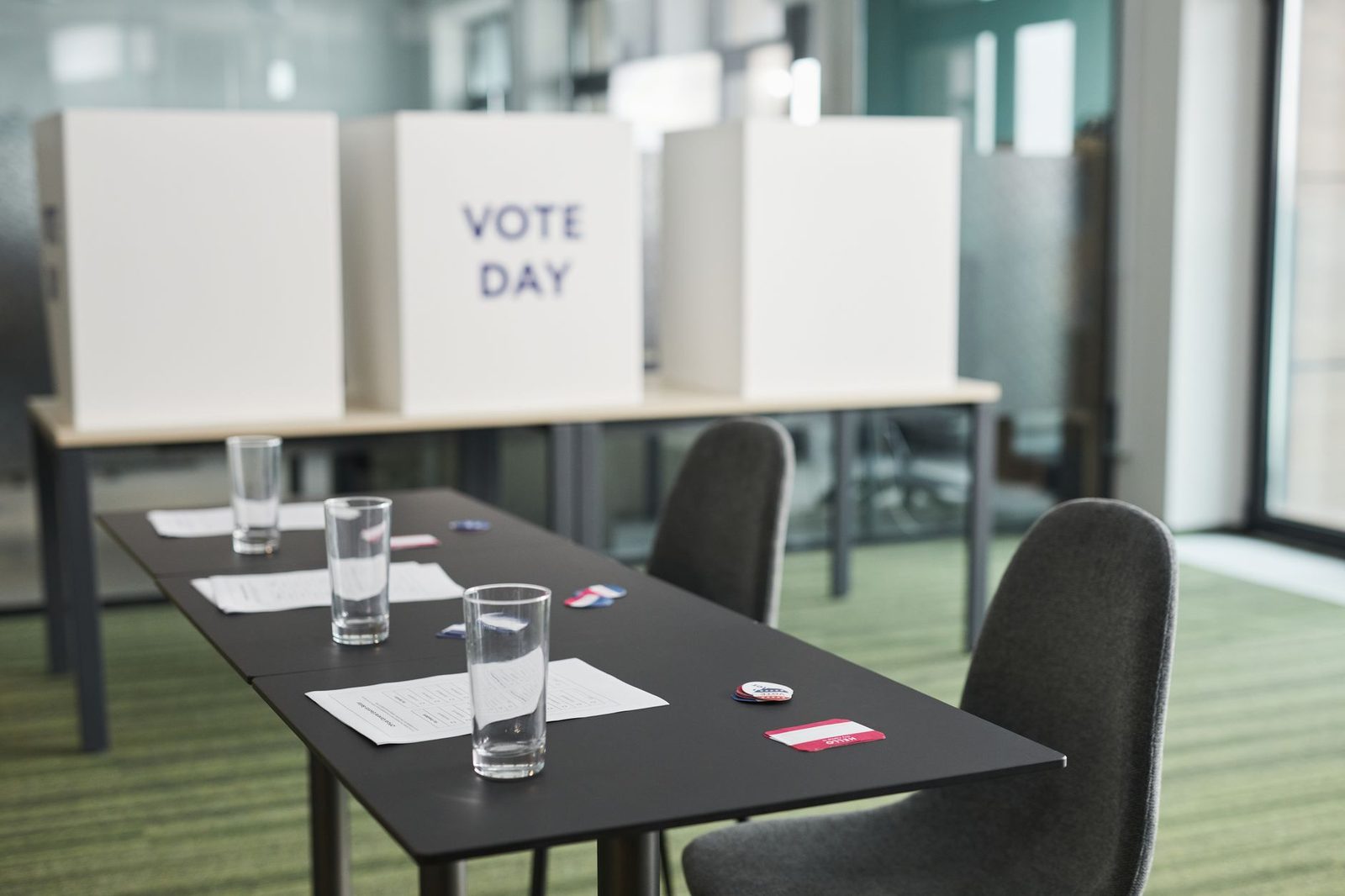 A prepared voting station with tables, chairs, and privacy booths set up in a meeting room ahead of an election