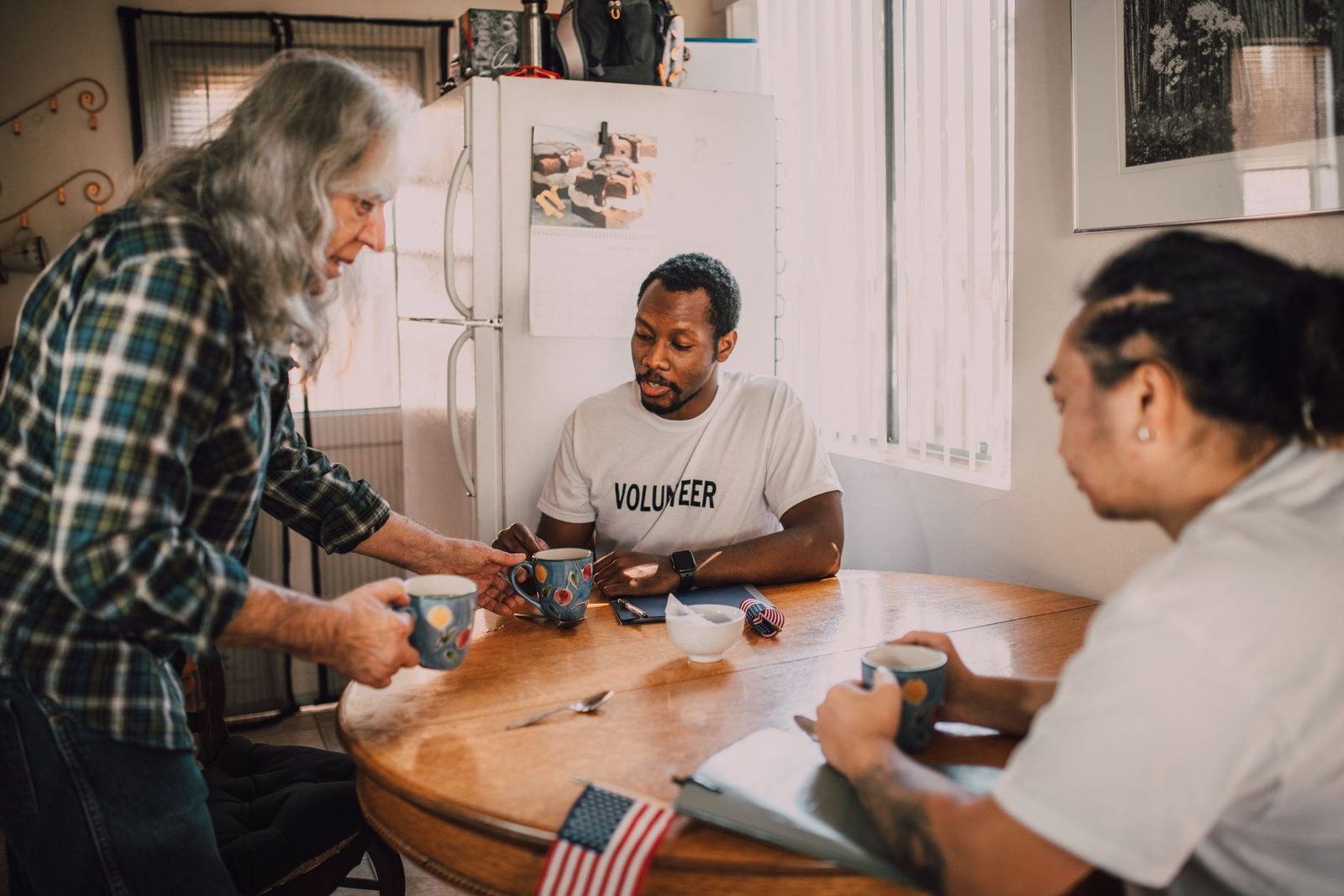 Volunteers planning around a table over coffee, the coordinating team a nonprofit texting program supports through CampaignCNX+