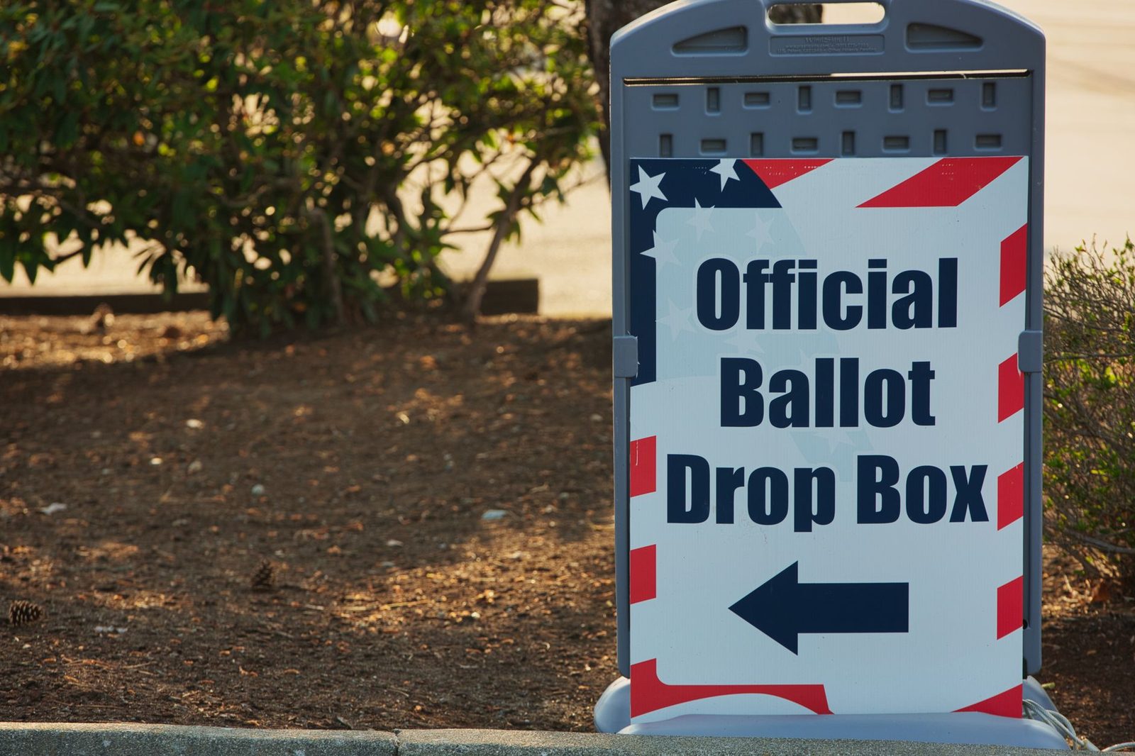 A sign pointing to an official ballot drop box during election season, the return location a mail-ballot chase text sends voters to
